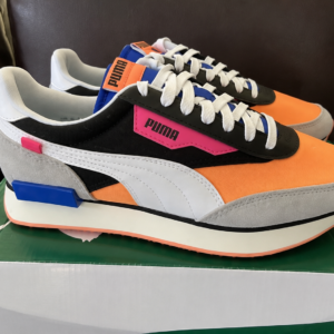 Pair of colorful PUMA sneakers with orange toe caps, black sides, white stripes, and grey suede heel on a green box.