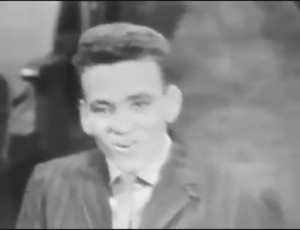Smiling boy in a suit and tie in a black-and-white vintage video.