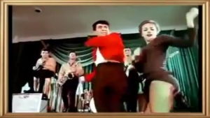 Dancers performing on a stage with a band in the background, wearing vintage outfits and energetic poses.