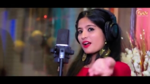 Woman in a red dress sings into a studio microphone wearing large over-ear headphones, recording.