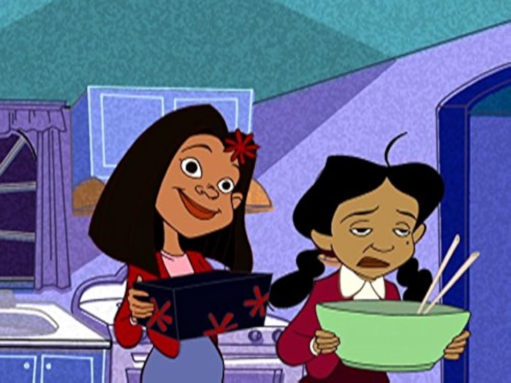 Two girls in a colorful kitchen: one smiles while holding a black box with red stars, the other carries a large green bowl with chopsticks and looks tired.