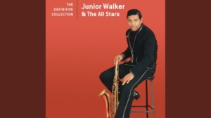 Album cover: Junior Walker & The All Stars – The Definitive Collection, man in a black suit seated with a saxophone against an orange background.